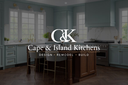 Elegant modern kitchen with seafoam cabinets, marble backsplash, and central wooden island; logo text “Cape & Island Kitchens” overlays the scene.