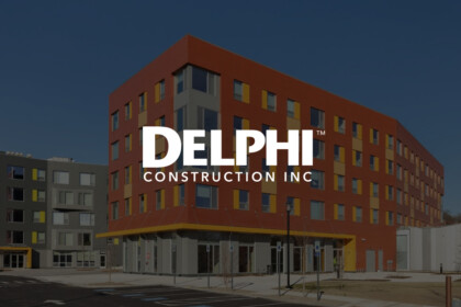Delphi Construction Inc building with a modern red and gray exterior, yellow window accents, and a large white logo overlaying the facade.